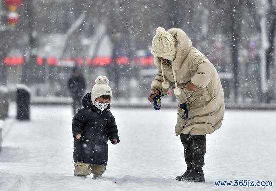 12月11日，新疆乌鲁木王人市迎来降雪。图为市民带着孩子在雪中玩耍。 中新社记者 刘新 摄